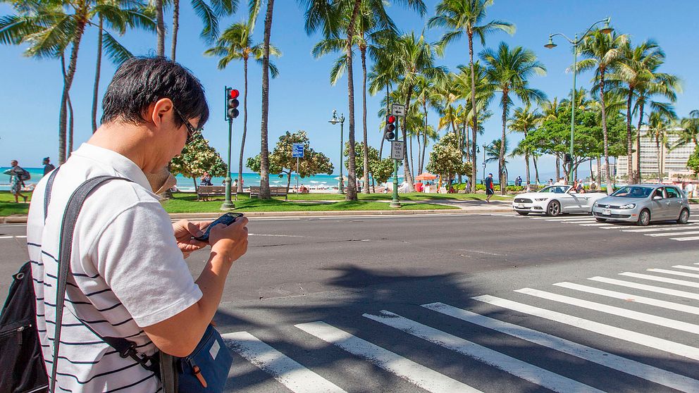 Arkivbild: En person kollar i mobilen när han korsar vägen i Honolulu, Hawaii. Något som han skulle kunna få böter för.