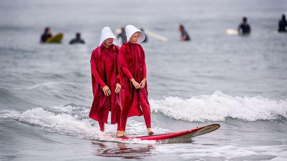Två personer deltar i en Halloween-surf i Kalifornien utklädda till karaktärer från den populära tv-serien Handmaid's Tail.