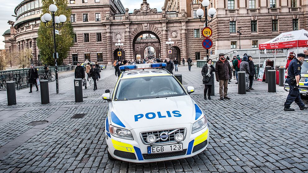 En polisbil framför riksdagen i Stockholm.