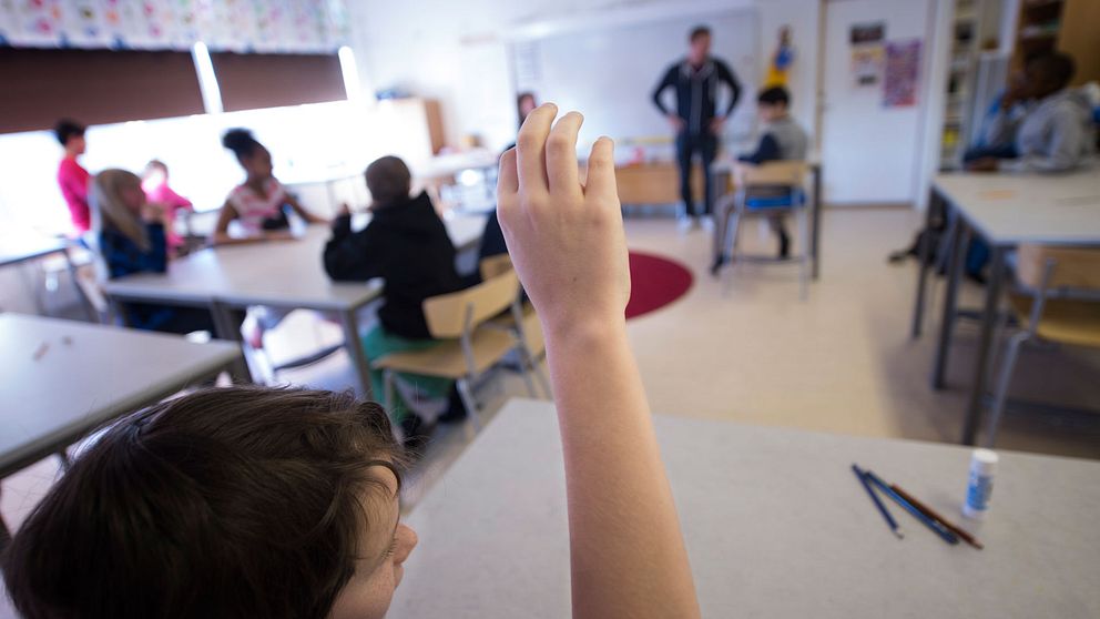Elever som räcker upp handen i ett klassrum