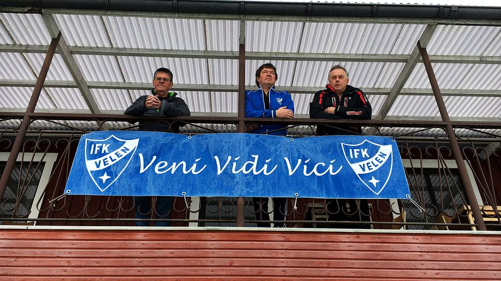 Lennart Björklund, till vänster, Per-Anders Persson, i mitten, och Jonny Johansson, till höger, står ovanför en banderoll med IFK Velens logga och orden ”veni vidi vici”