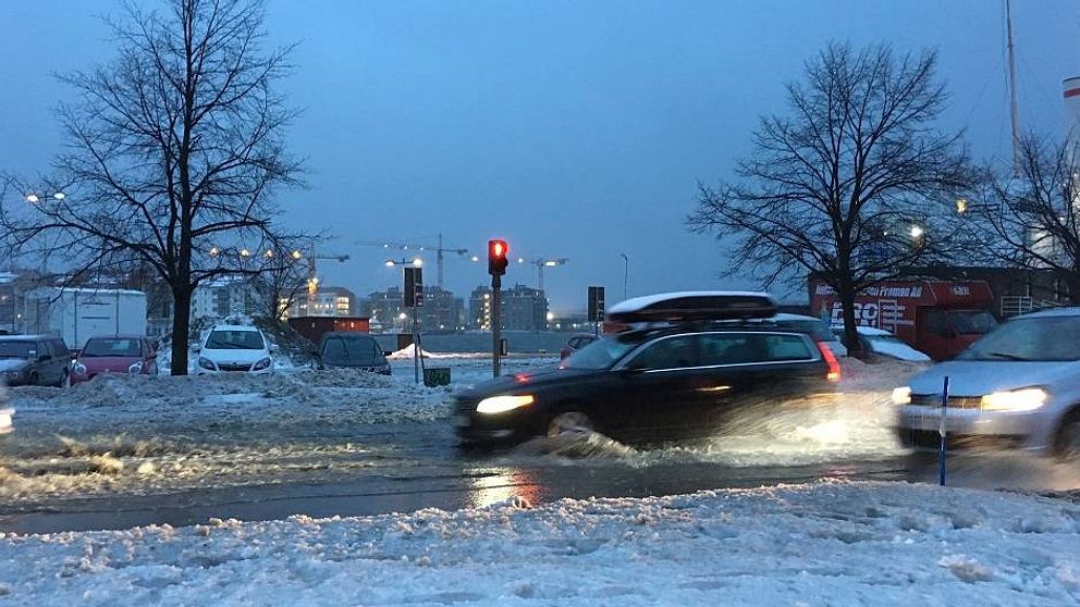 bilar kör i snömodd i stan