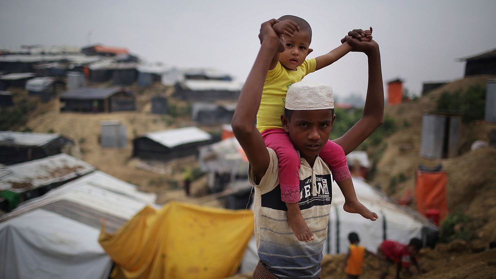 En rohingya pojke bär ett barn på sina axlar i flyktinglägret Jamtoli i Bangladesh.