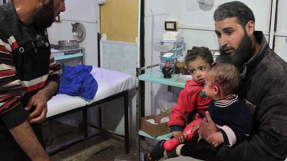 En man tar hand om två barn efter bombattacken i Syrien. De får hjälp av sjukhuspersonal.
