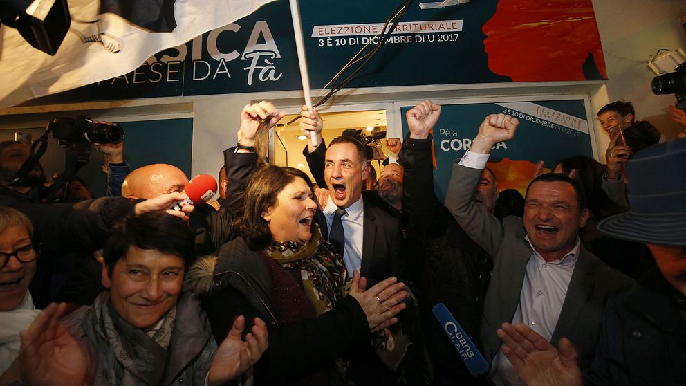 Pè a Corsicas toppnamn Gilles Simeoni (i mitten) firar valframgångarna med sina anhängare.