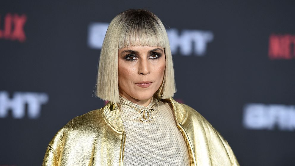 Skådespelaren Noomi Rapace i guldjacka, guldtröja och guldhalsband.