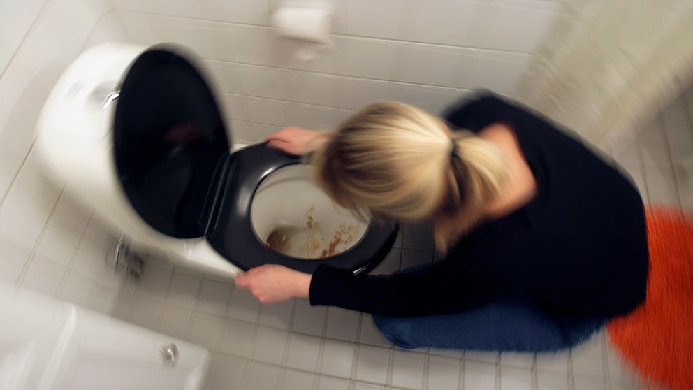 En kvinna spyr i en toalett.