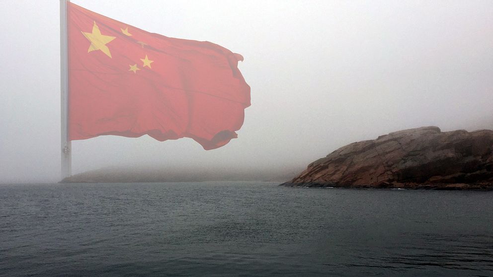 Dimmig bild av kusten intill en kinesisk flagga