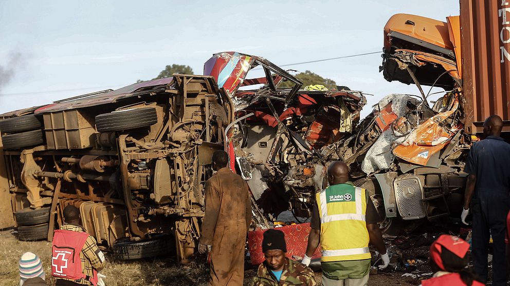 Räddningspersonal vid de demolerade fordonen. Bussolyckan inträffade nära staden Nakuru i mellersta Kenya.