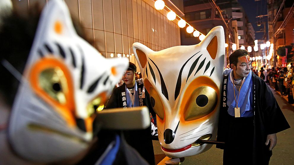Nyårsfirare med rävmasker förbereder sig för en parad i Tokyo.