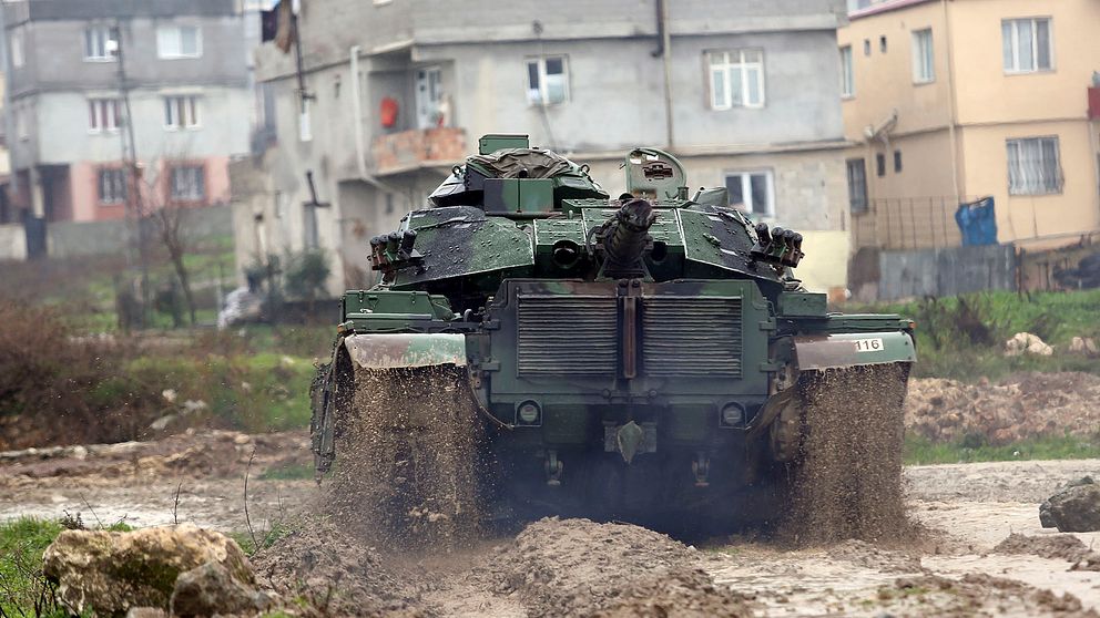 En grön turkisk stridsvagn som åker nedför en lerväg.