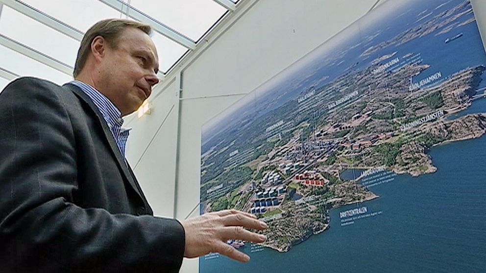 Peter Abrahamsson intill flygbild av preemraffs anläggning i Lysekil.