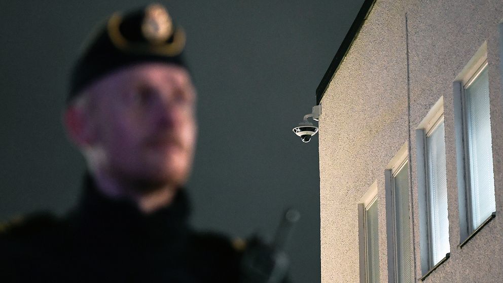 En övervakningskamera på Rinkeby torg och en polis i oskärpa