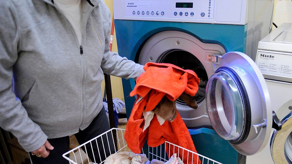 En kvinna tar ur tvätt ur tvättmaskinen.
