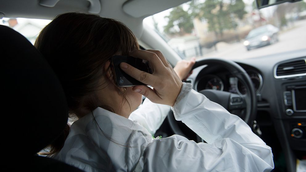 Kvinna talar i mobiltelefon i bil.