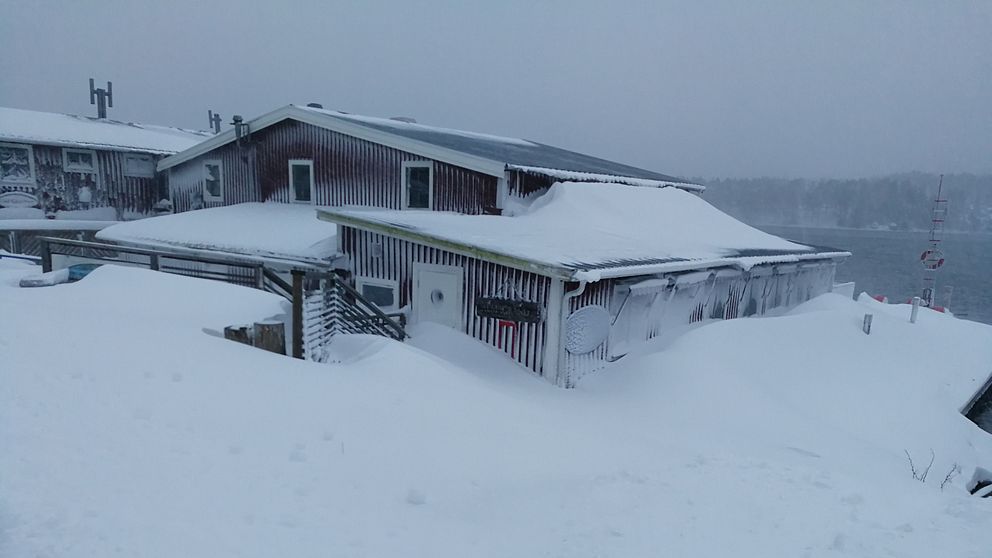 Ett rött hus täckt av stora mängder snö.