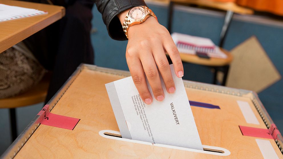 En kvinna röstar i en vallokal.