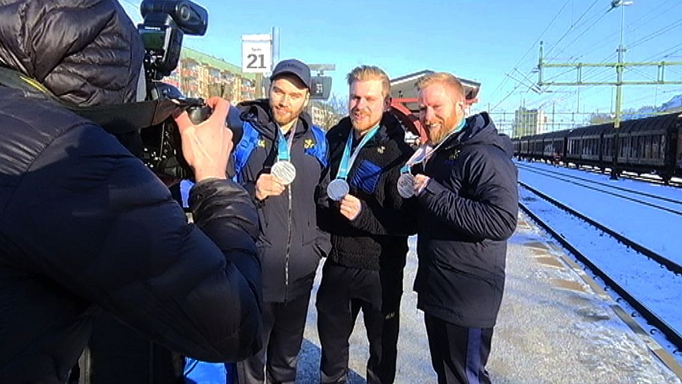 Oskar Eriksson, Rasmus Wranå och Niklas Edin visar upp sina medaljer för en kamera