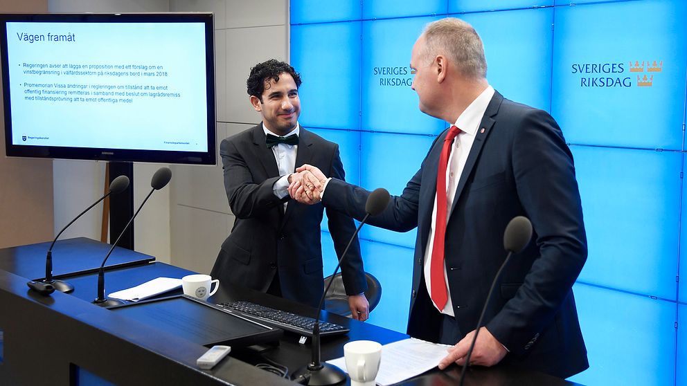 Civilminister Ardalan Shekarabi och Vänsterpartiets ledare Jonas Sjöstedt skakar hand vid en presskonferens.