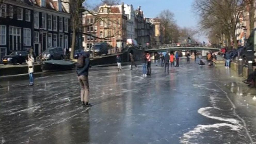Folk åker skridskor i kanal i Amsterdam.