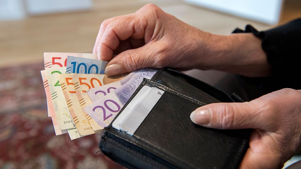 En kvinna håller i en plånbok med sedlar.