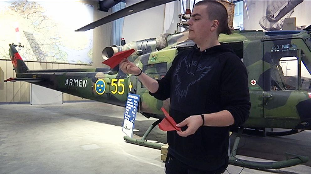 en kille med pappersflygplan framför en helikopter på museum