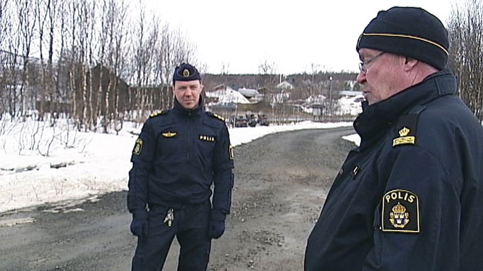 Två poliser står på en väg.