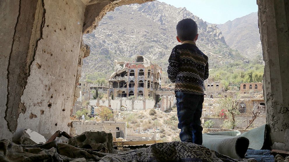 En pojke tittar ut på sönderbombade hus efter ett flyganfall mot staden Taez i södra Yemen.