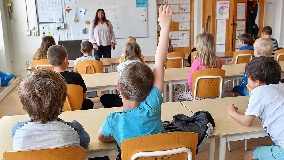 unga skolbarn i klassrum, lärare framme vid tavlan