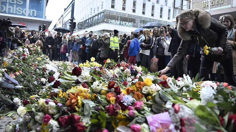 Ett blomhav omringat av folksamling på Drottninggatan.