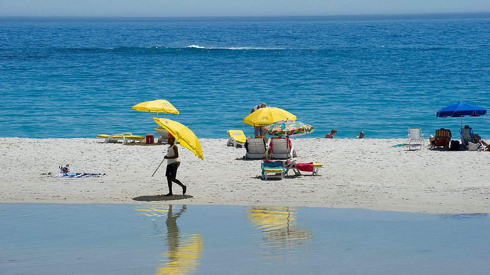 Solbad på stranden vid Camps bay i Sydafrika.