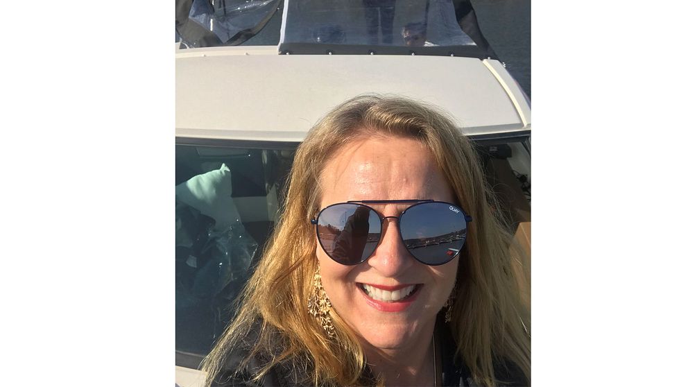 Camilla i solglasögon framför en båt