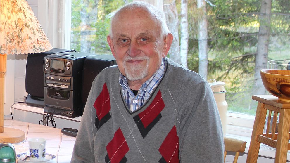 Bild på Jöran Lundberg, som sitter framför en stereo i hemmamiljö med en kaffekopp bredvid sig.