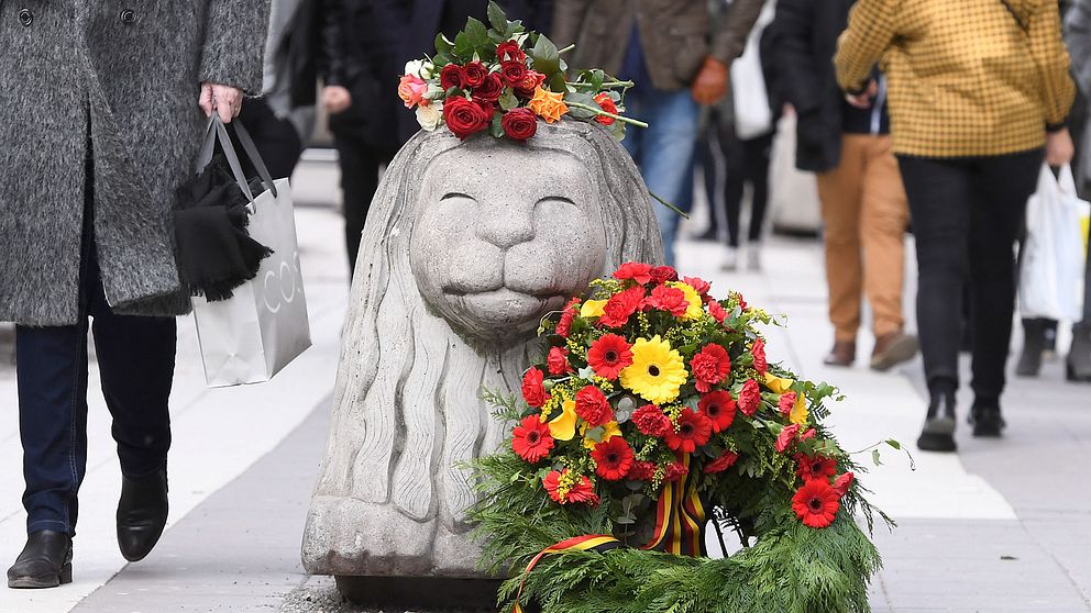 Blommor och en krans pryder ett av Drottninggatans betonglejon på årsdagen av terrordådet.