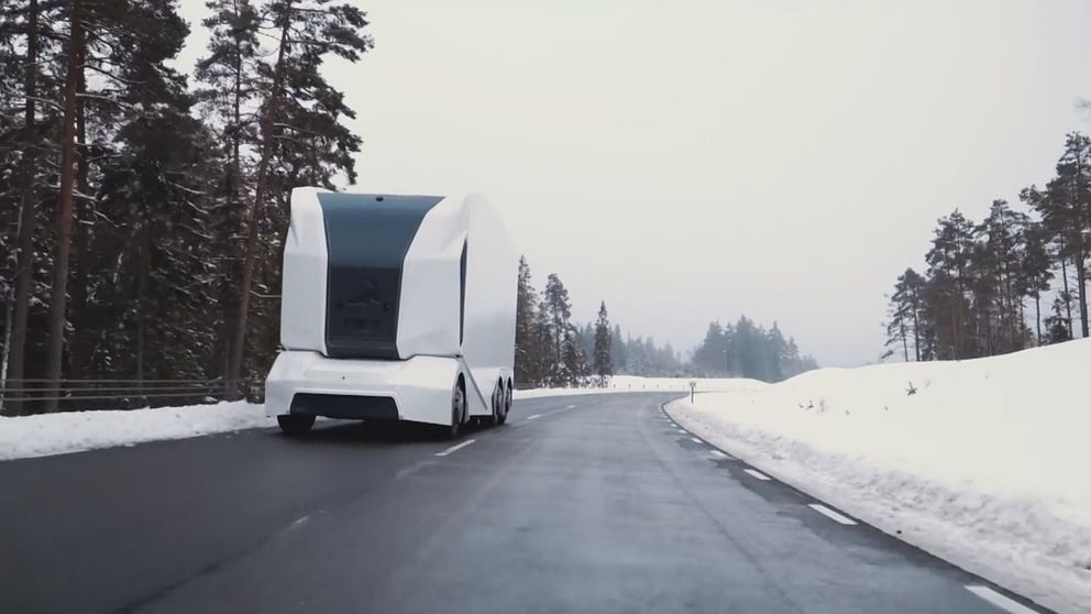 vit och svart lastbil utan förarhytt som kör på landsväg i vintermiljö