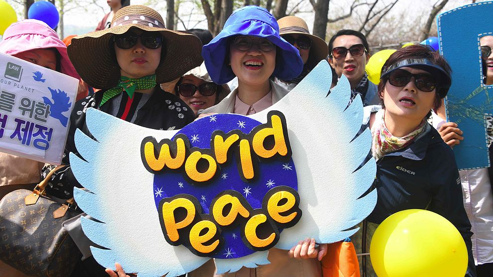 Medlemmar i den kvinnliga sydkorenanska fredsgruppen håller upp en skylt där det står ”World peace”