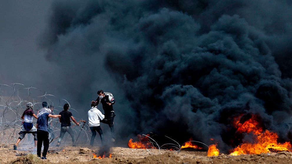 Palestinska protestanter försöker dra ner en del av stängslet vid gränsen till Israel.