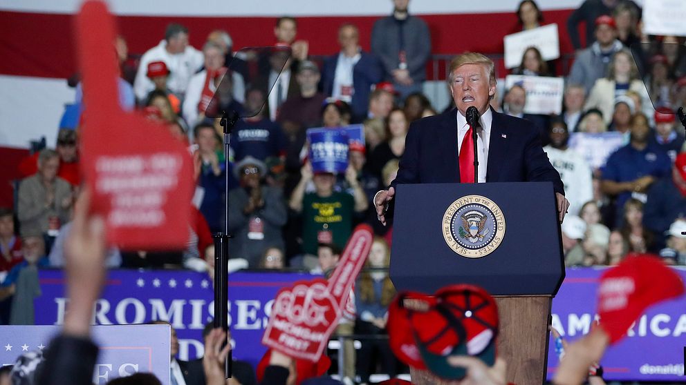 USAs president Donald Trump står vid ett podium men många anhängare runtomkring