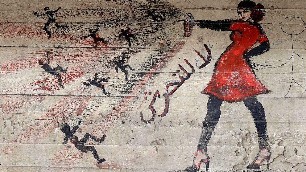 Graffitimålning i Egypten föreställande en kvinna som sprayar bort män och sexuella trakasserier.