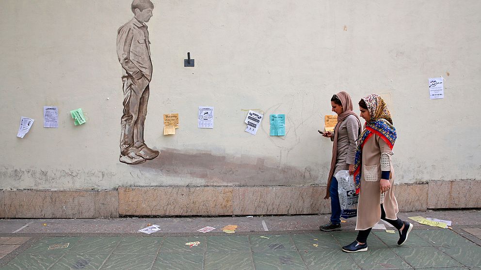 Två kvinnor går på gatan i Irans huvudstad Teheran.