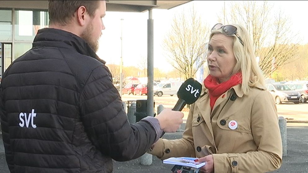 Reporter står med mikrofon i hand och intervjuar socialdemokraternas Anna Johansson i kappa och röd scarf.