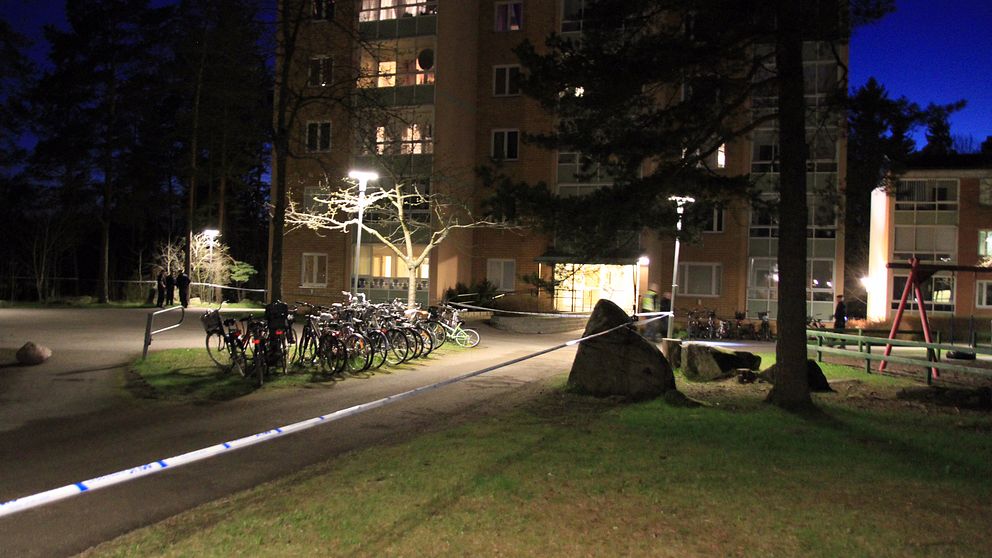 Polisavspärrningar vid ett lägenhetshus på kvällen.