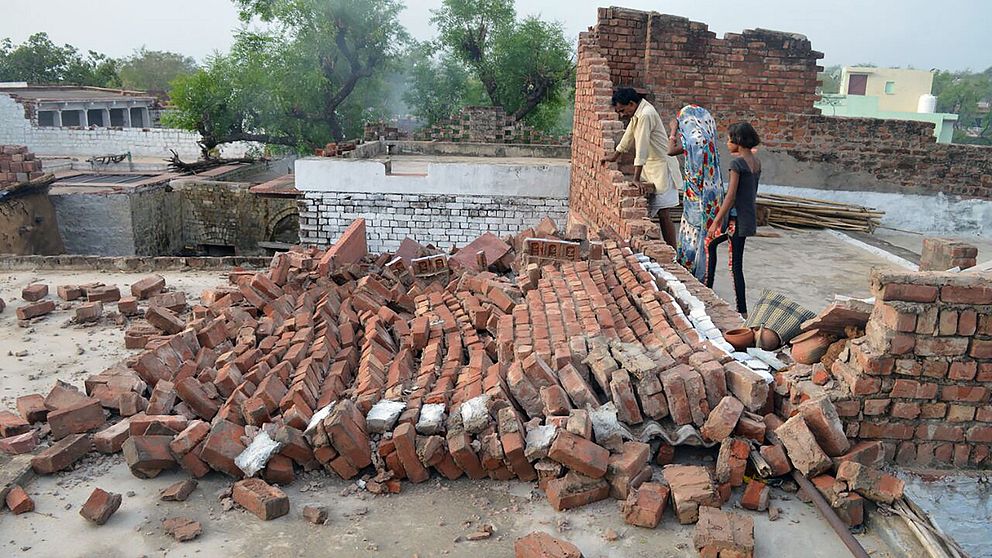 Människor i Agra tittar på en byggnad som förstörts i stormen.
