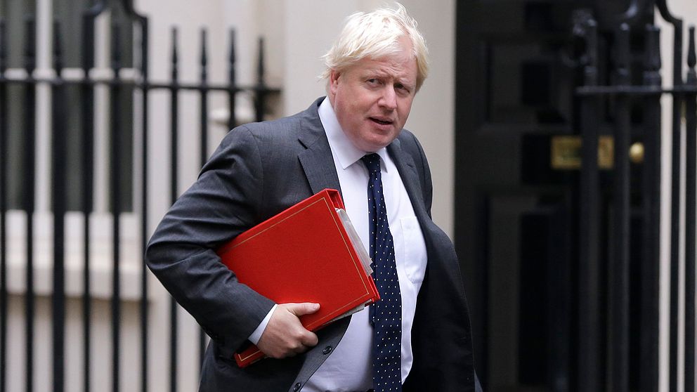 Storbritanniens utrikesminister Boris Johnson gåendes med en röd pärm under armen.