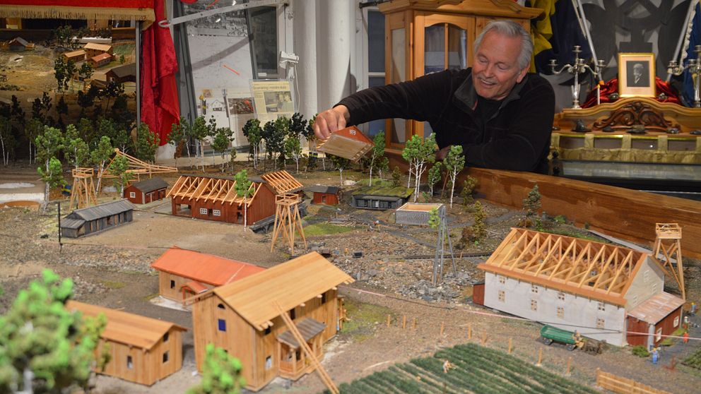 Hans Harnisch lyfter på taket till ett av husen i  modellen av gruvfältet i Kaveltorp i Kopparberg.