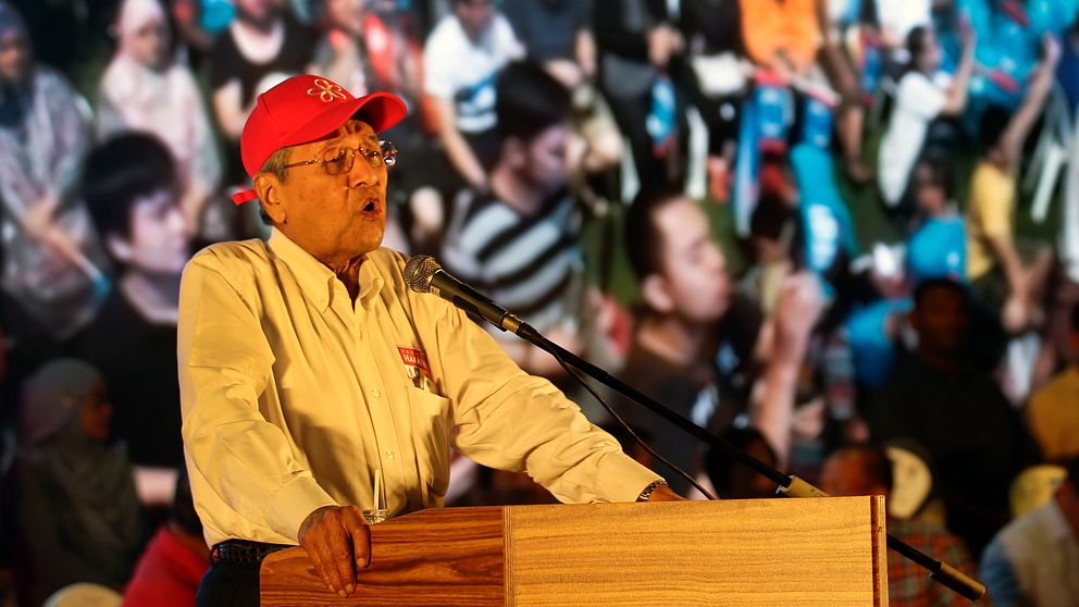 Den malayisiska före detta ledaren Mahathir Mohamad iklädd röd keps talar inför en folkmassa i Kuala Lumpur