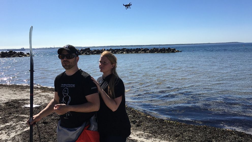 Dövblinde Torbjörn Svensson på stranden tillsammans med en kvinnlig tolk.