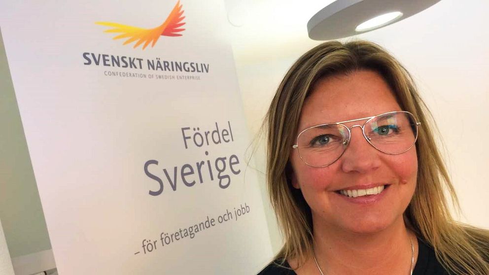 På bilden syns en kvinna med glasögon. Bakom henne finns en skärm som det står Svenskt Näringsliv på.