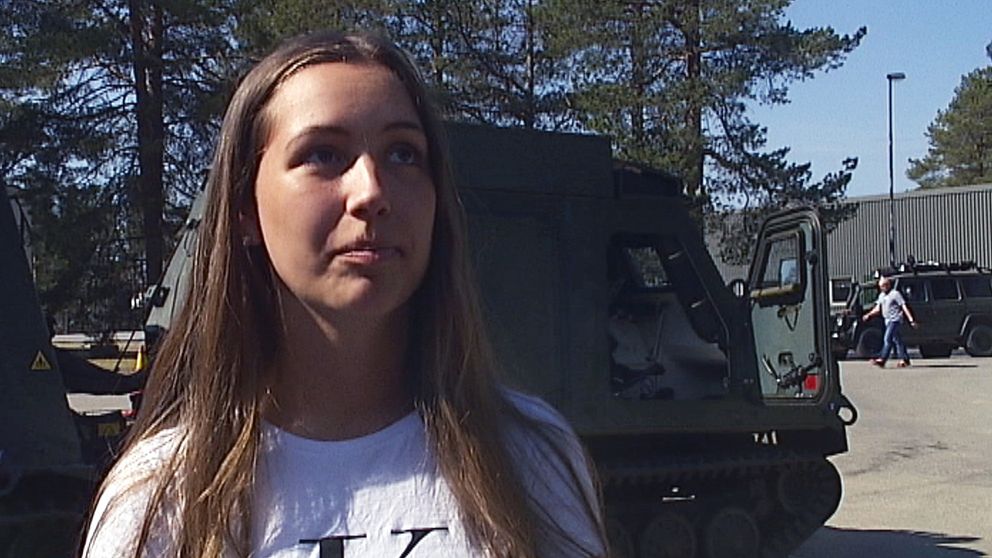 En ung kvinna som intervjuad framför ett militärfordon.