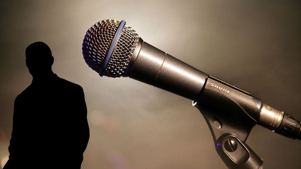 En silhuett av en man tillsammans med en mikrofon.